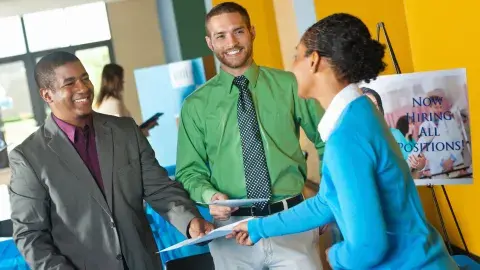 Young professional submitting resume to business team at job fair