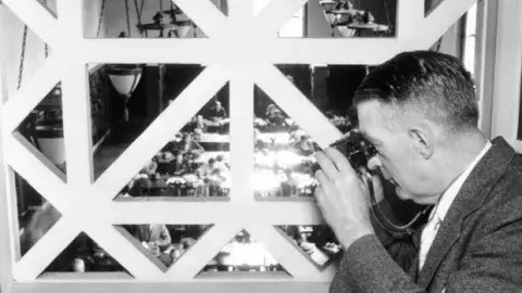 men with binoculars looking in a window