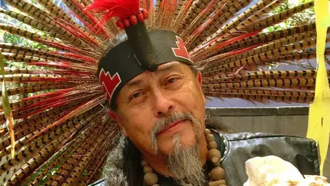 Native American man wearing a headband with feathers