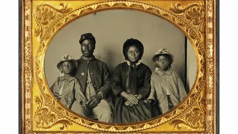 Quarter-Plate Ambrotype taken between 1863 and 1865. Image depicts a Black Union Army private and his wife and twin daughters.