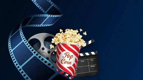 An unspooled reel of film curls around an overflowing popcorn tub and a film clapper.