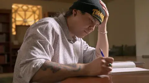 River Garza writing at desk in library