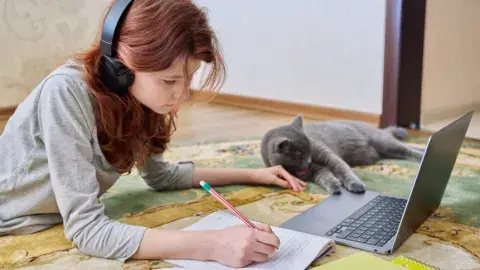 Girl studying on the floor with her cat. 