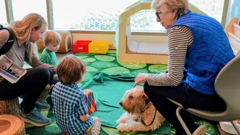 family sits on carpet with dog