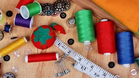 Sewing materials with threads, needles, and measuring tape.
