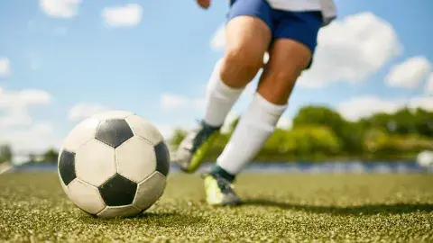 childs legs kicking a soccer ball