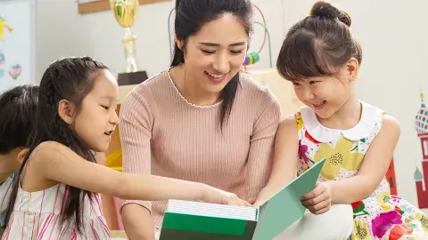 An adult reading a book to two children.
