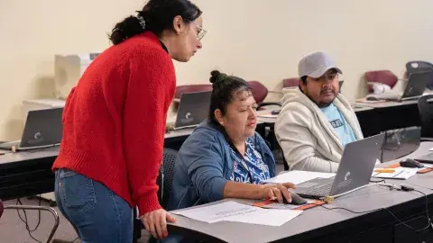 Librarian provides assistance to person on laptop