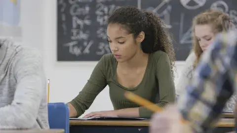 Teenage girl in a classroom working at her desk. 