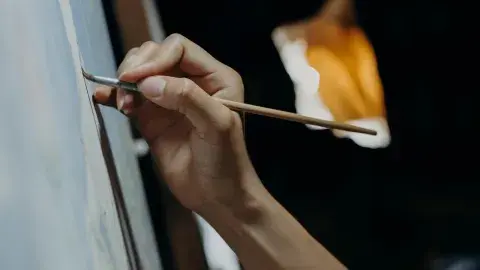 A color photo of a hand painting on canvas