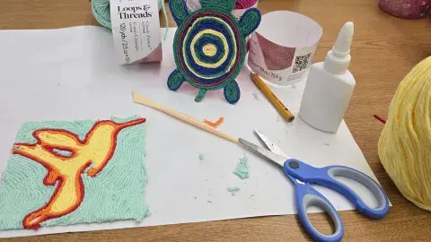 a table with supplies to make craft including scissors, glue, yarn, 