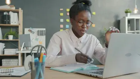 Woman infront writing in front of laptop