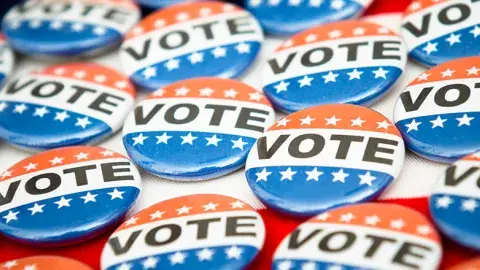 Several red, white, and blue buttons with the word vote written in black.