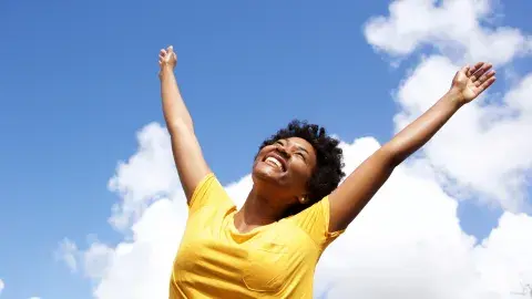 Cheerful young woman with raised hands