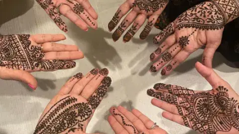 Hands featuring hand drawn henna designs.