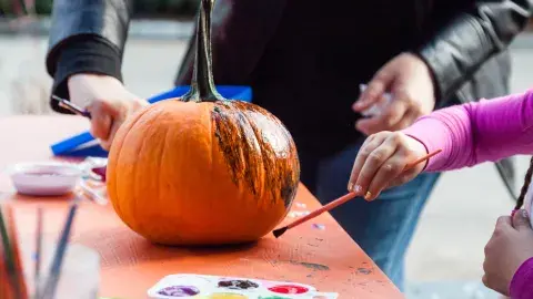 Two people painting a pumpkin.
