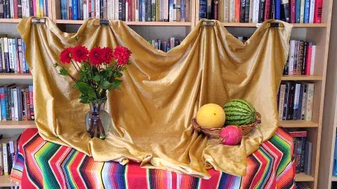 A still life with a basket with fruits and a vase with red flowers
