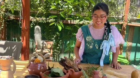 A woman wearing an apron in front of handmade clay objects. 