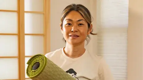 Yoga teacher Sayuri is holding a tatami mat