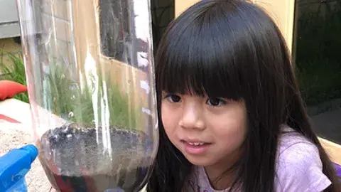 young girl observes a science experiment