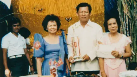 Group of people standing behind a table covered with Filipino food