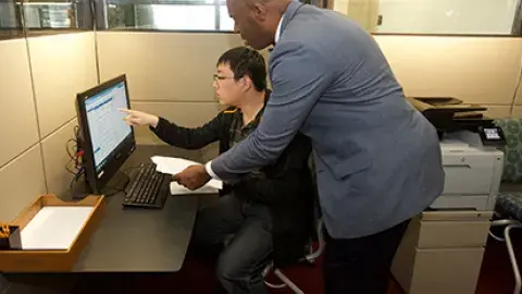 a job counselor helping a young man on a computer