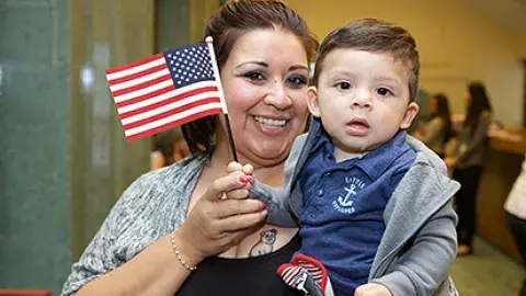 a woman waving a U.S. flag and holding a baby