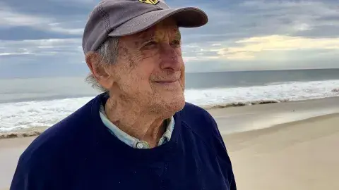André Gregory in a cap and sweater at the beach
