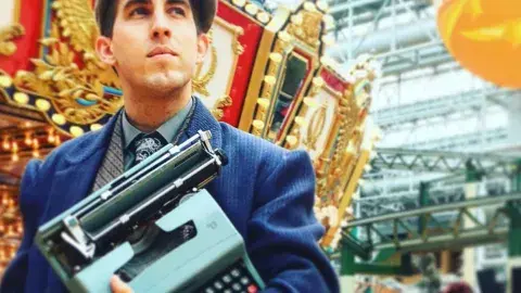 Brian Sonia-Wallace holding a typewriter
