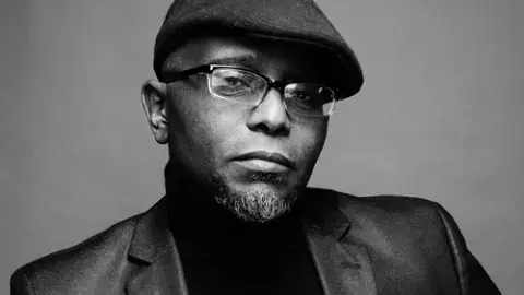 Tyehimba Jess in a jacket and cap. photo credit: John Midgley
