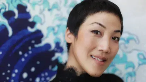 traci kato-kiriyama in front of a blue wave painting