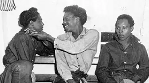 Three people sit together with mixed expressions.