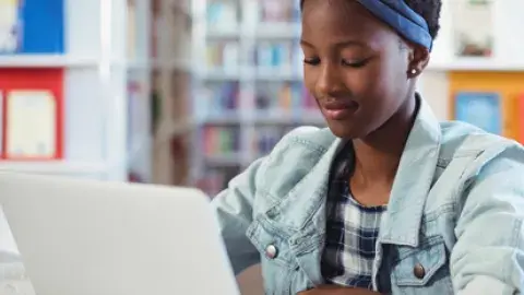 student sitting at the library with her laptop