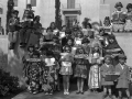 Children dressed in the costumes of many different countries hold signs indicating the languages in which books are available at the Los Angeles Public Library, ca 1939 