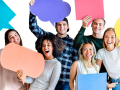 Six young people stand in a group against a white background. They are smiling and holding large thought bubbles of different colors.