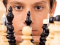 Young boy looking at chess pieces.