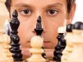 A young chess player is looking at the chess board
