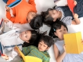 kids laying on the ground in a circle each reading a book