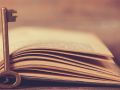 an open book with a key on the top of the spine