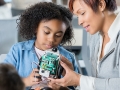 child and adult working on robotics