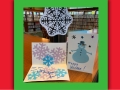 A paper snowflake and two paper greeting cards with images of snowflakes and a snowman.