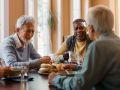 A group of seniors are having a meeting over coffee and snacks