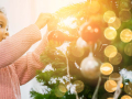 A child putting an ornament on a Christmas tree.