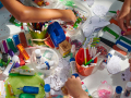 Table covered in white tablecoth, arts and crafts on table with children's hands in view.