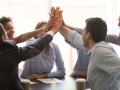 office workers high fiving over a desk
