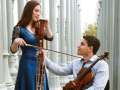 The two members of Dyad are posing with bassoon and violin in front of lampposts