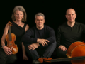 Three members of the Fibonacci Trio pose with instruments in front of a black background