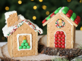 Two gingerbread houses made of graham crackers, white frosting, and various colorful candies are on display. 