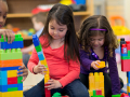 Three girls build with Lego building blocks.