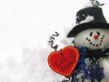 Snowman sitting in snow with a heart-shaped sign that says "let it snow"